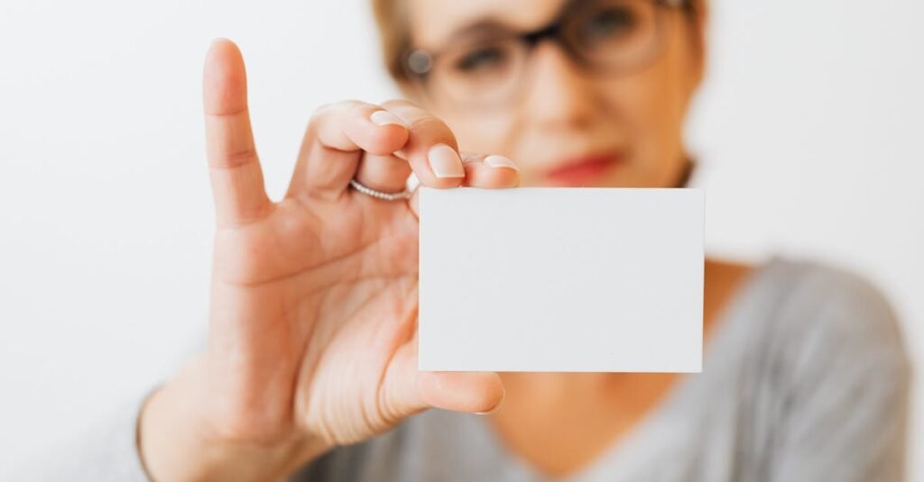 Close-up of a woman holding a blank business card with a blurred background for copyspace.